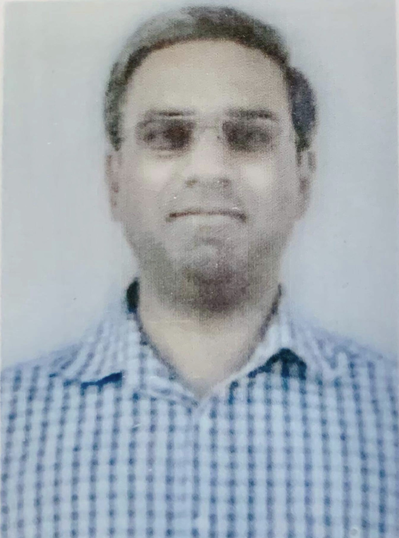 Jeanine White smiling in a red plaid shirt and tortoise shell glasses